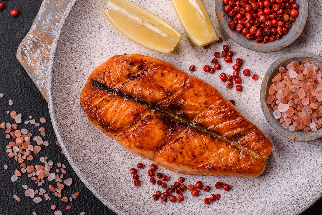 Bife de salmão delicioso cozido fresco com especiarias e ervas assadas em uma grelha. Comida saudável de frutos do mar