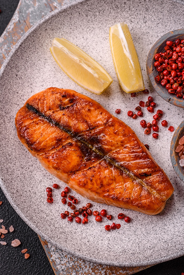 Bife de salmão delicioso cozido fresco com especiarias e ervas assadas em uma grelha. Comida saudável de frutos do mar