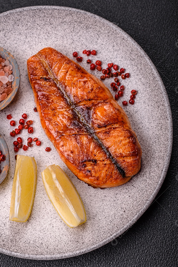 Bife de salmão delicioso cozido fresco com especiarias e ervas assadas em uma grelha. Comida saudável de frutos do mar
