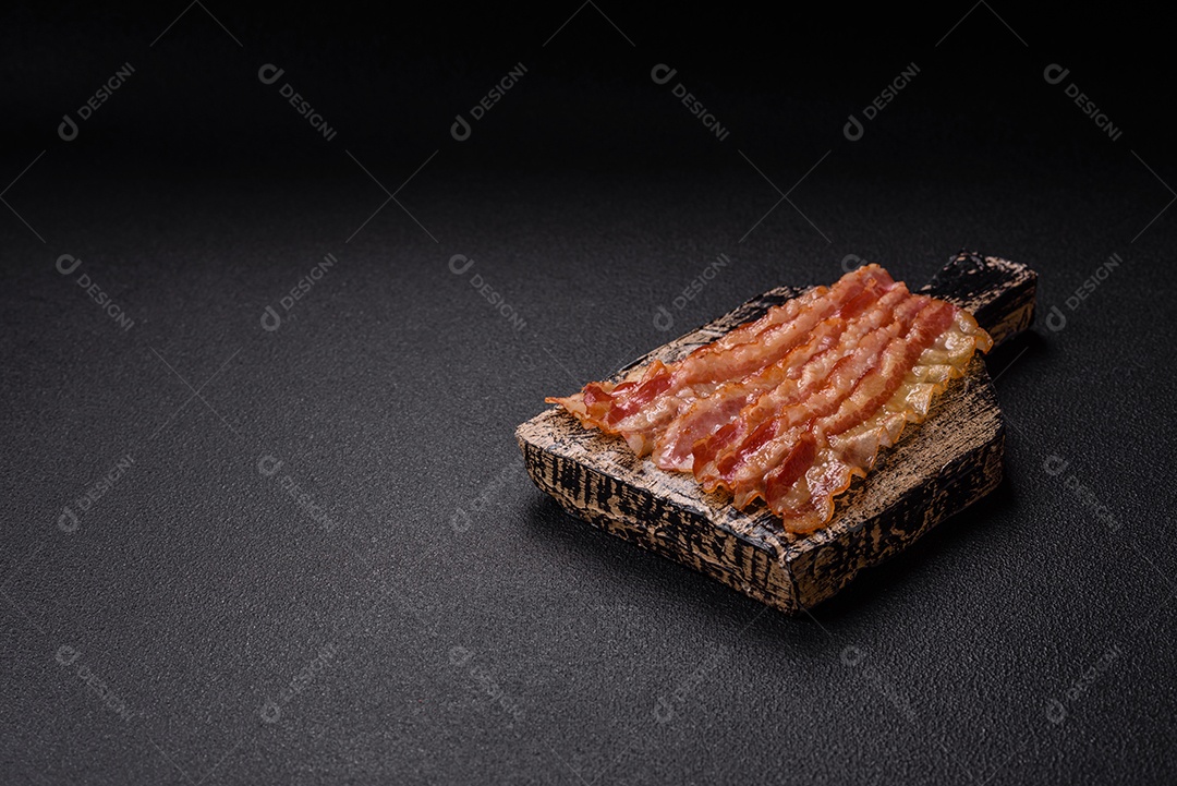 Delicioso bacon em forma de fatias com sal, especiarias e ervas sobre um fundo escuro de concreto