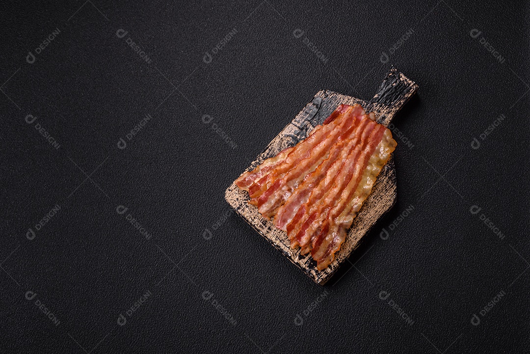 Delicioso bacon em forma de fatias com sal, especiarias e ervas sobre um fundo escuro de concreto