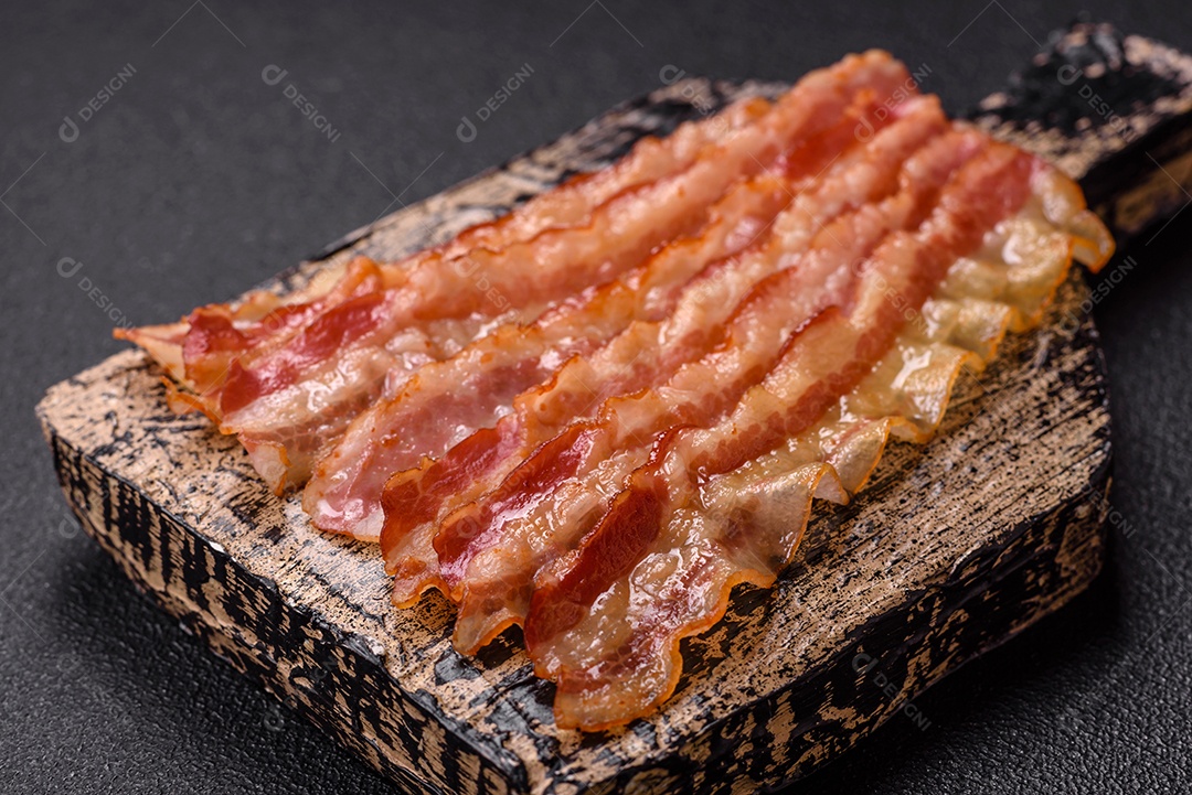 Delicioso bacon em forma de fatias com sal, especiarias e ervas sobre um fundo escuro de concreto