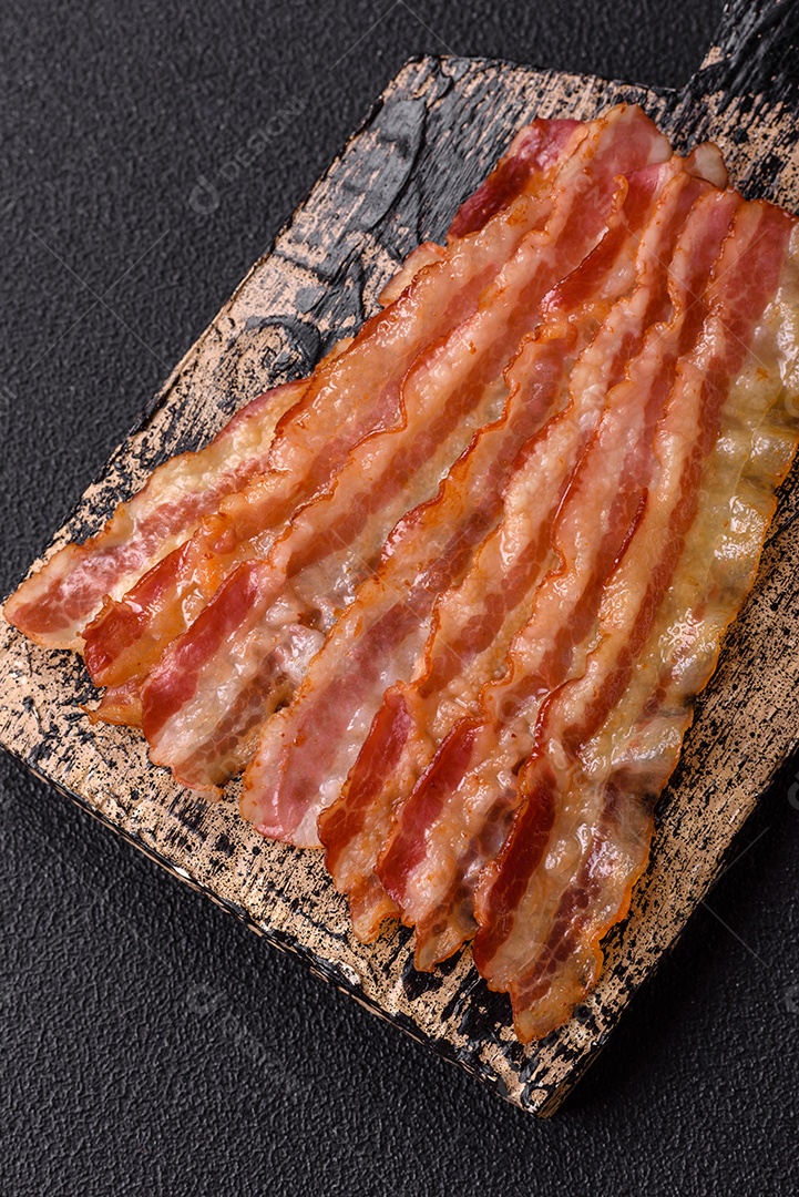 Delicioso bacon em forma de fatias com sal, especiarias e ervas sobre um fundo escuro de concreto