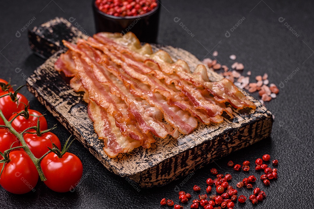 Delicioso bacon em forma de fatias com sal, especiarias e ervas sobre um fundo escuro de concreto