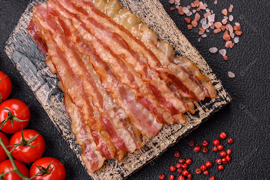 Delicioso bacon em forma de fatias com sal, especiarias e ervas sobre um fundo escuro de concreto