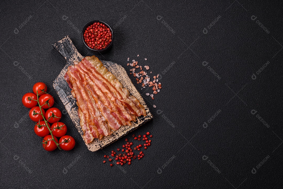 Delicioso bacon em forma de fatias com sal, especiarias e ervas sobre um fundo escuro de concreto