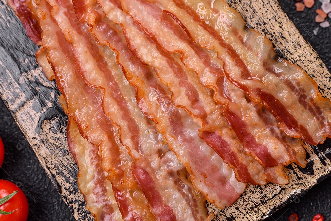 Delicioso bacon em forma de fatias com sal, especiarias e ervas sobre um fundo escuro de concreto