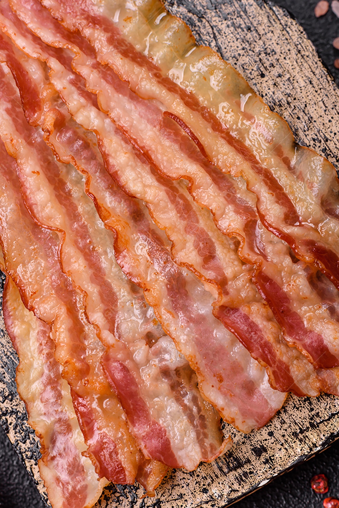 Delicioso bacon em forma de fatias com sal, especiarias e ervas sobre um fundo escuro de concreto
