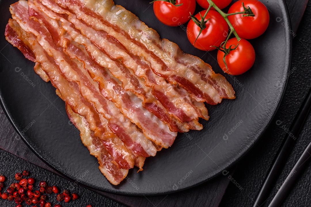 Delicioso bacon em forma de fatias com sal, especiarias e ervas sobre um fundo escuro de concreto