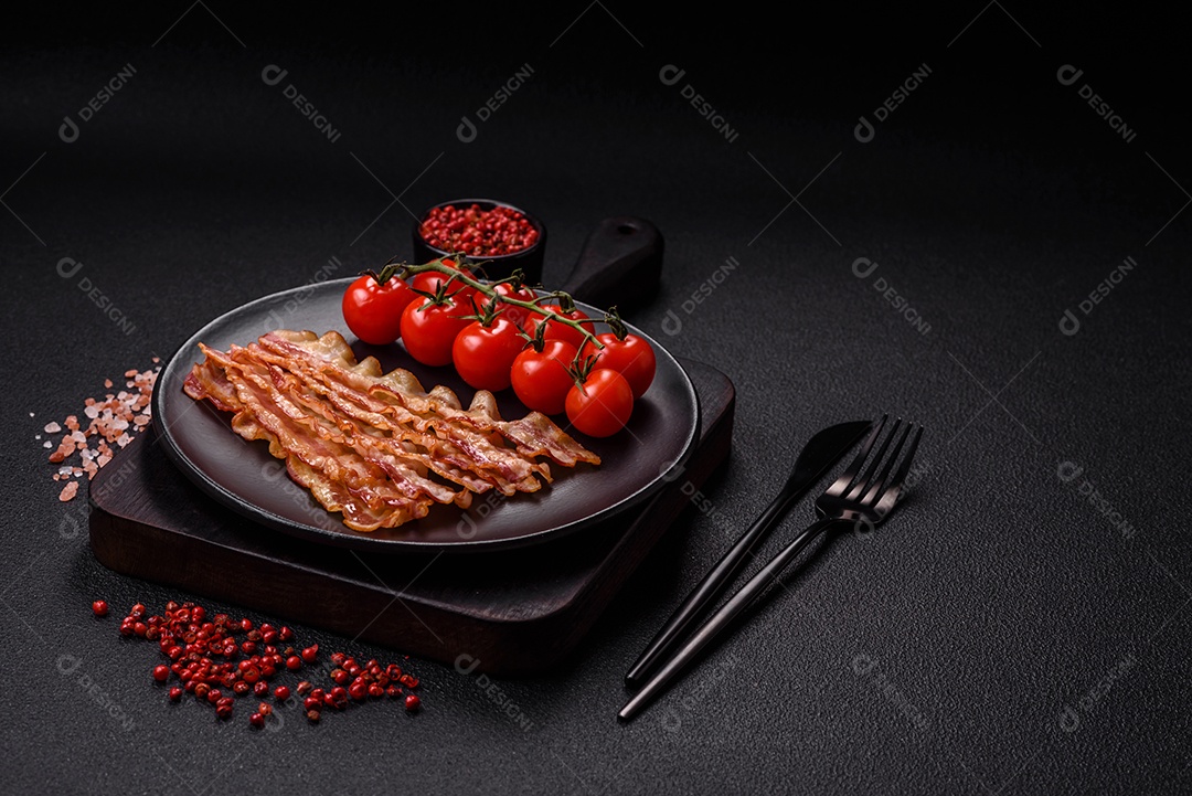 Delicioso bacon em forma de fatias com sal, especiarias e ervas sobre um fundo escuro de concreto