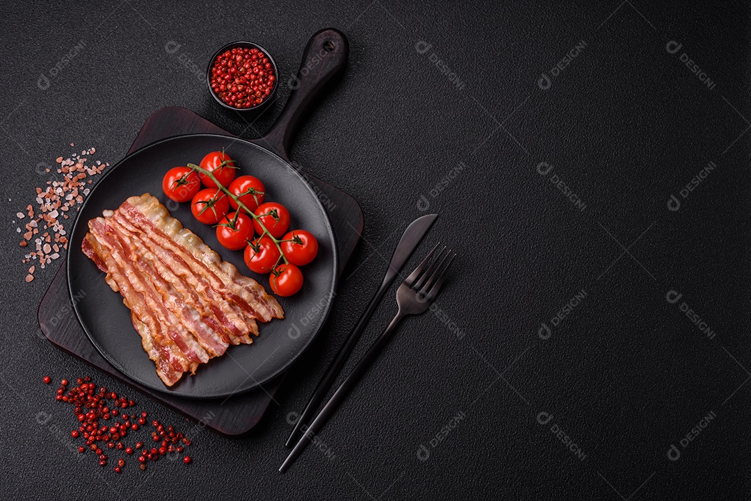 Delicioso bacon em forma de fatias com sal, especiarias e ervas sobre um fundo escuro de concreto