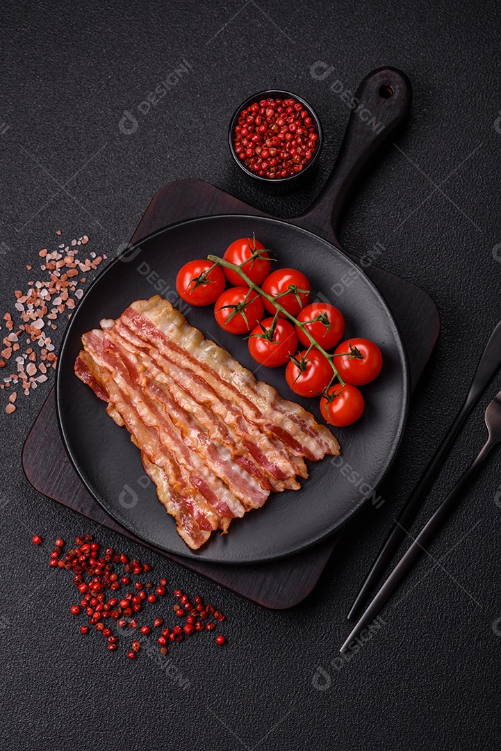 Delicioso bacon em forma de fatias com sal, especiarias e ervas sobre um fundo escuro de concreto