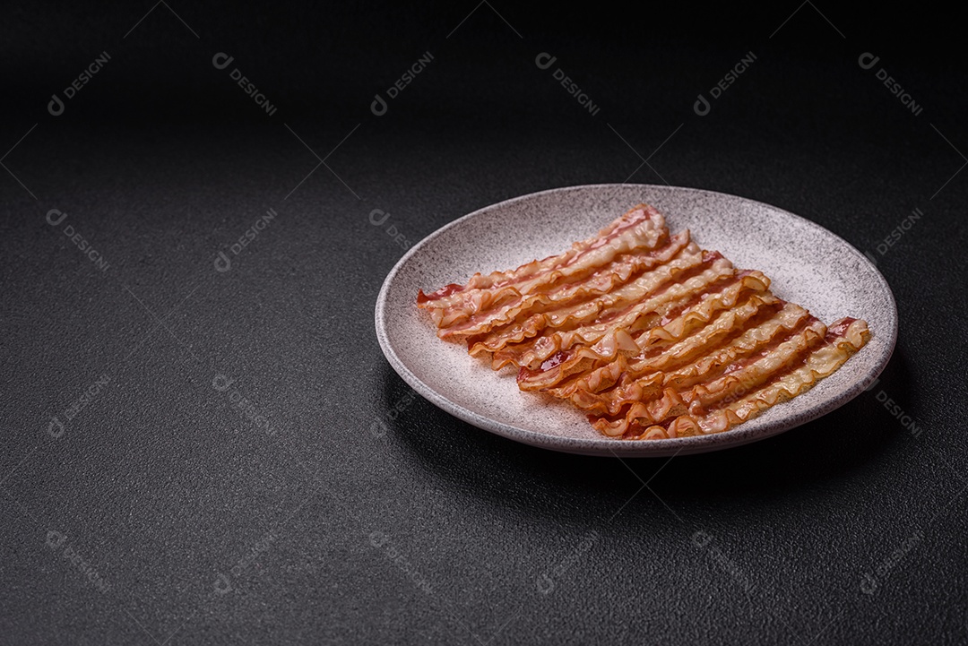 Delicioso bacon em forma de fatias com sal, especiarias e ervas sobre um fundo escuro de concreto