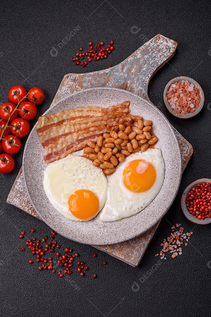 Café da manhã inglês com ovos fritos, bacon, feijão, tomate, especiarias e ervas. Um início de dia saudável e nutritivo