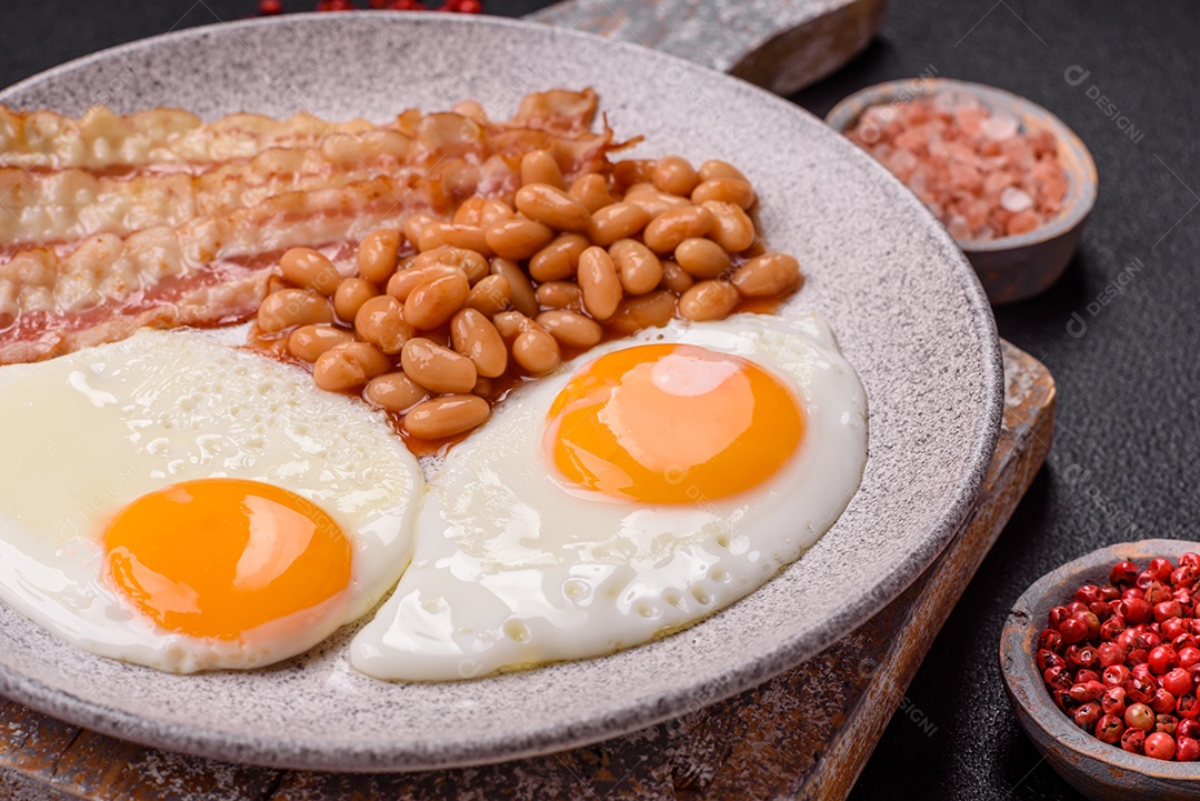 Café da manhã inglês com ovos fritos, bacon, feijão, tomate, especiarias e ervas. Um início de dia saudável e nutritivo