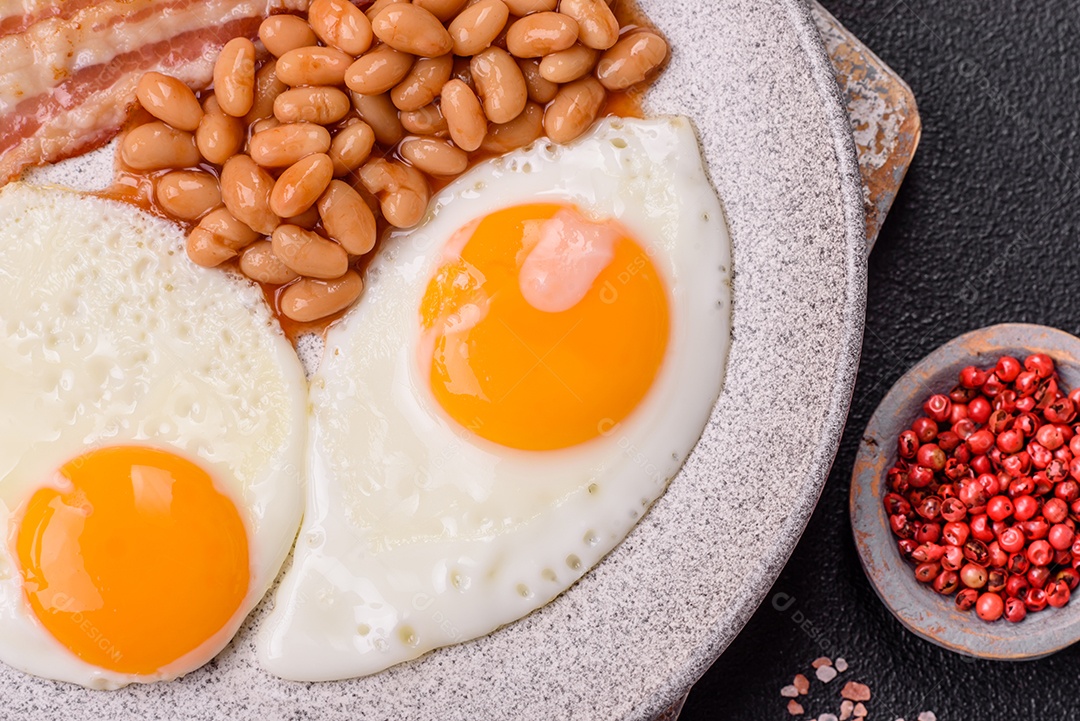 Café da manhã inglês com ovos fritos, bacon, feijão, tomate, especiarias e ervas. Um início de dia saudável e nutritivo