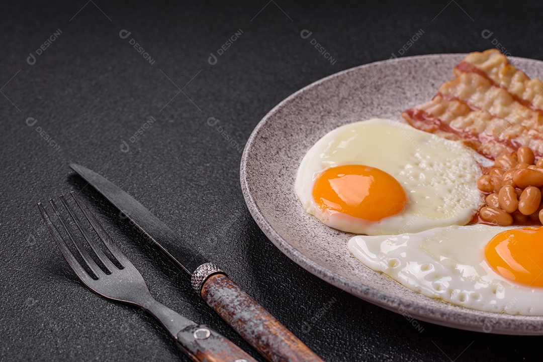 Café da manhã inglês com ovos fritos, bacon, feijão, tomate, especiarias e ervas. Um início de dia saudável e nutritivo