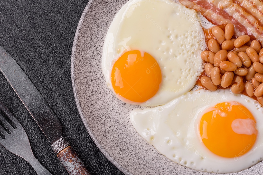 Café da manhã inglês com ovos fritos, bacon, feijão, tomate, especiarias e ervas. Um início de dia saudável e nutritivo