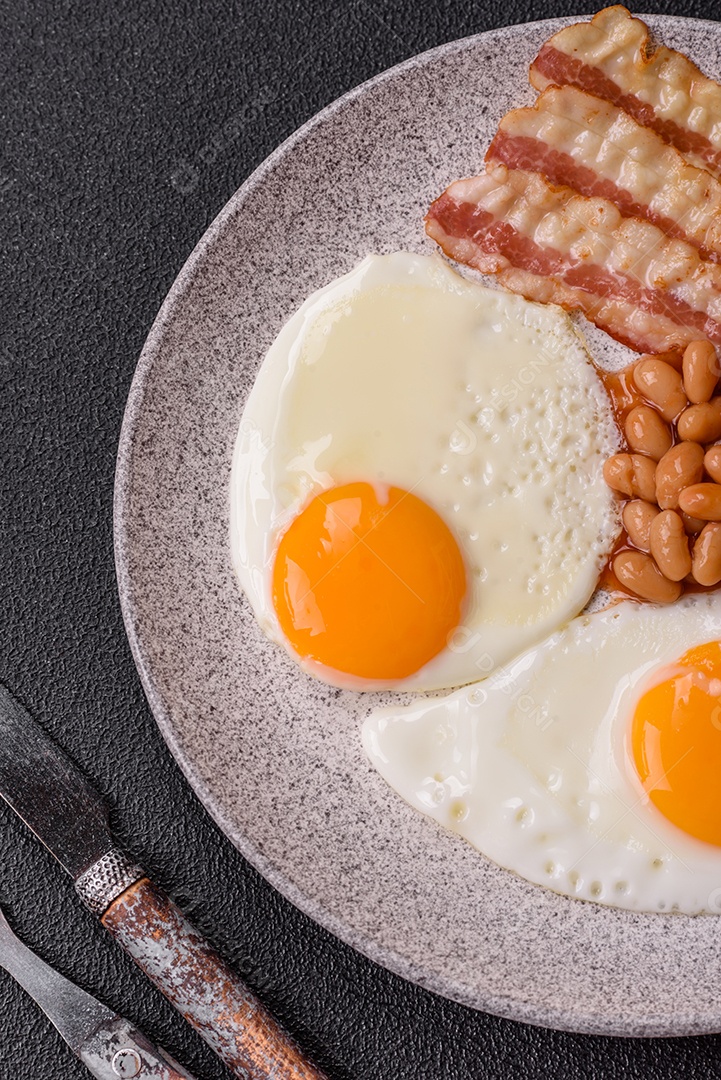 Café da manhã inglês com ovos fritos, bacon, feijão, tomate, especiarias e ervas. Um início de dia saudável e nutritivo