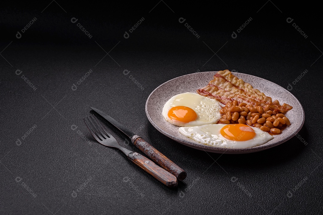 Café da manhã inglês com ovos fritos, bacon, feijão, tomate, especiarias e ervas. Um início de dia saudável e nutritivo