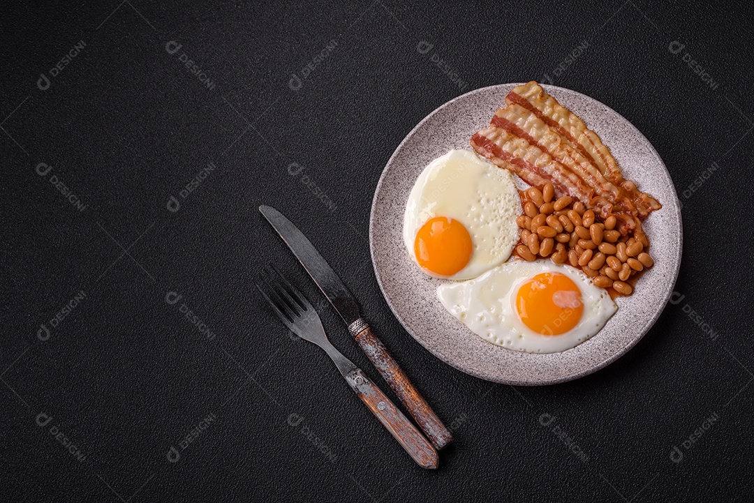 Café da manhã inglês com ovos fritos, bacon, feijão, tomate, especiarias e ervas. Um início de dia saudável e nutritivo