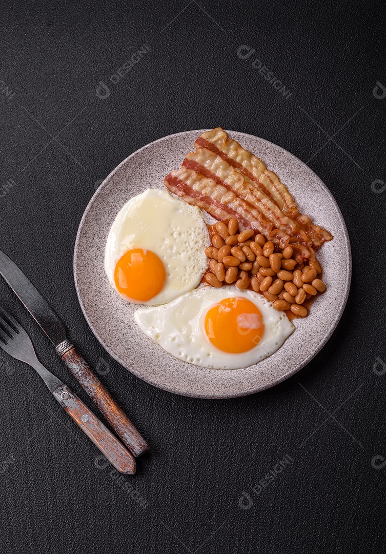 Café da manhã inglês com ovos fritos, bacon, feijão, tomate, especiarias e ervas. Um início de dia saudável e nutritivo