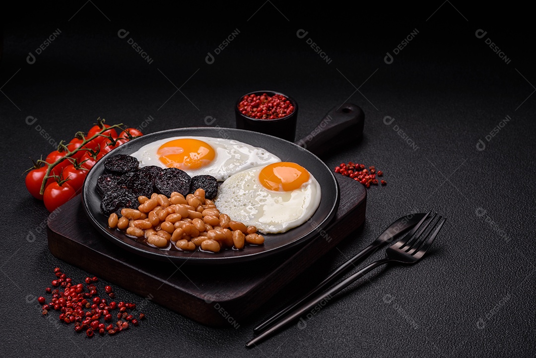 Café da manhã inglês com ovos fritos, bacon, feijão, tomate, especiarias e ervas. Um início de dia saudável e nutritivo