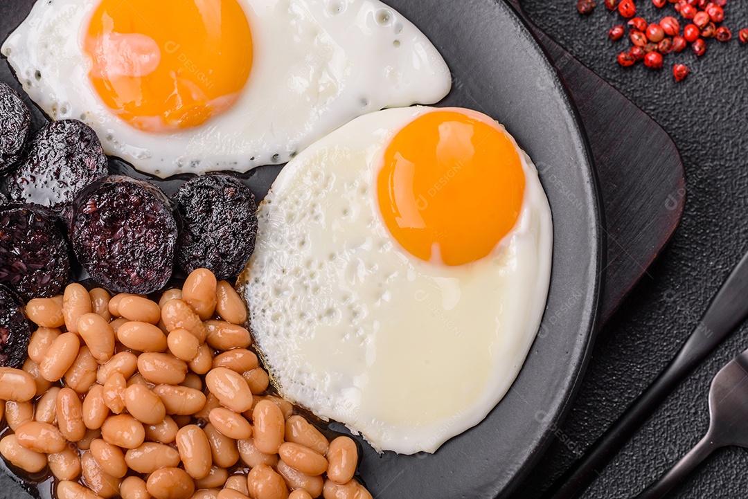 Café da manhã inglês com ovos fritos, bacon, feijão, tomate, especiarias e ervas. Um início de dia saudável e nutritivo