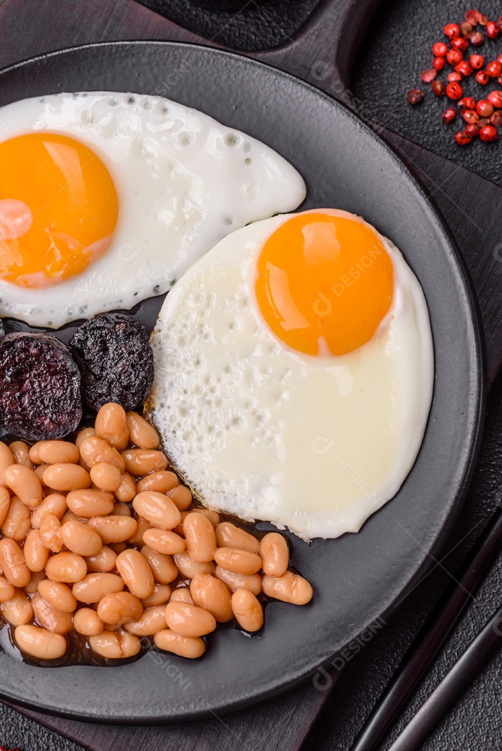 Café da manhã inglês com ovos fritos, bacon, feijão, tomate, especiarias e ervas. Um início de dia saudável e nutritivo