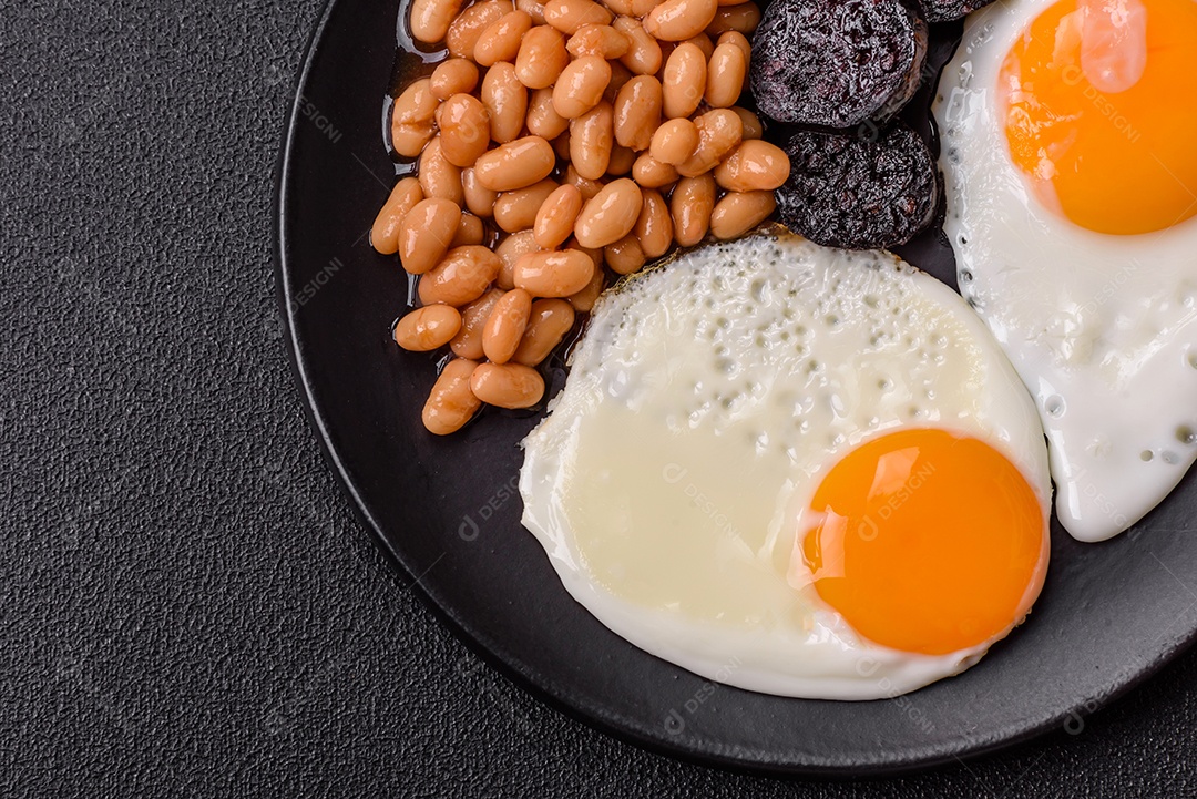 Café da manhã inglês com ovos fritos, bacon, feijão, tomate, especiarias e ervas. Um início de dia saudável e nutritivo