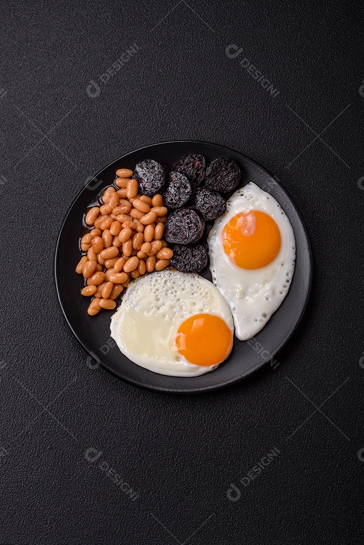 Café da manhã inglês com ovos fritos, bacon, feijão, tomate, especiarias e ervas. Um início de dia saudável e nutritivo