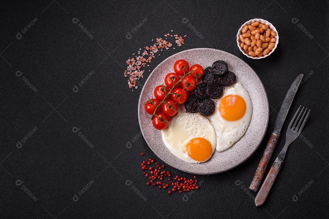 Café da manhã inglês com ovos fritos, bacon, feijão, tomate, especiarias e ervas. Um início de dia saudável e nutritivo