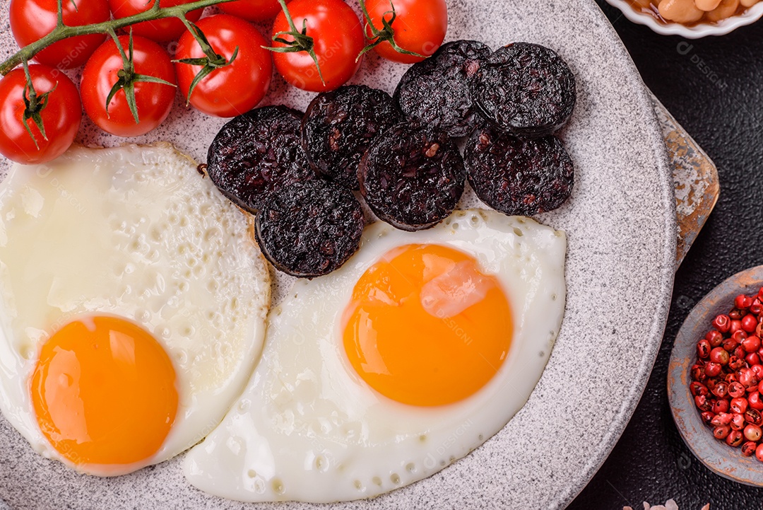 Café da manhã inglês com ovos fritos, bacon, feijão, tomate, especiarias e ervas. Um início de dia saudável e nutritivo