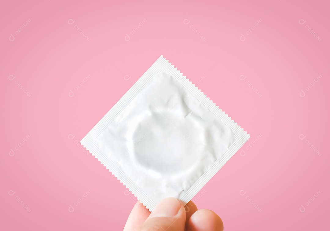 Mão com camisinha sobre fundo rosa