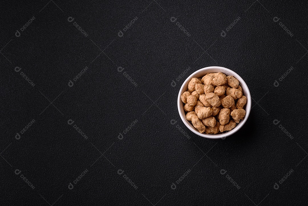 Pellets de carne de soja seca, alimentos dietéticos para cozinha vegana e vegetariana em fundo escuro de concreto