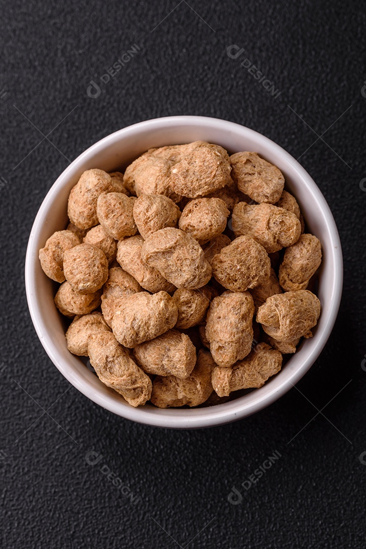 Pellets de carne de soja seca, alimentos dietéticos para cozinha vegana e vegetariana em fundo escuro de concreto