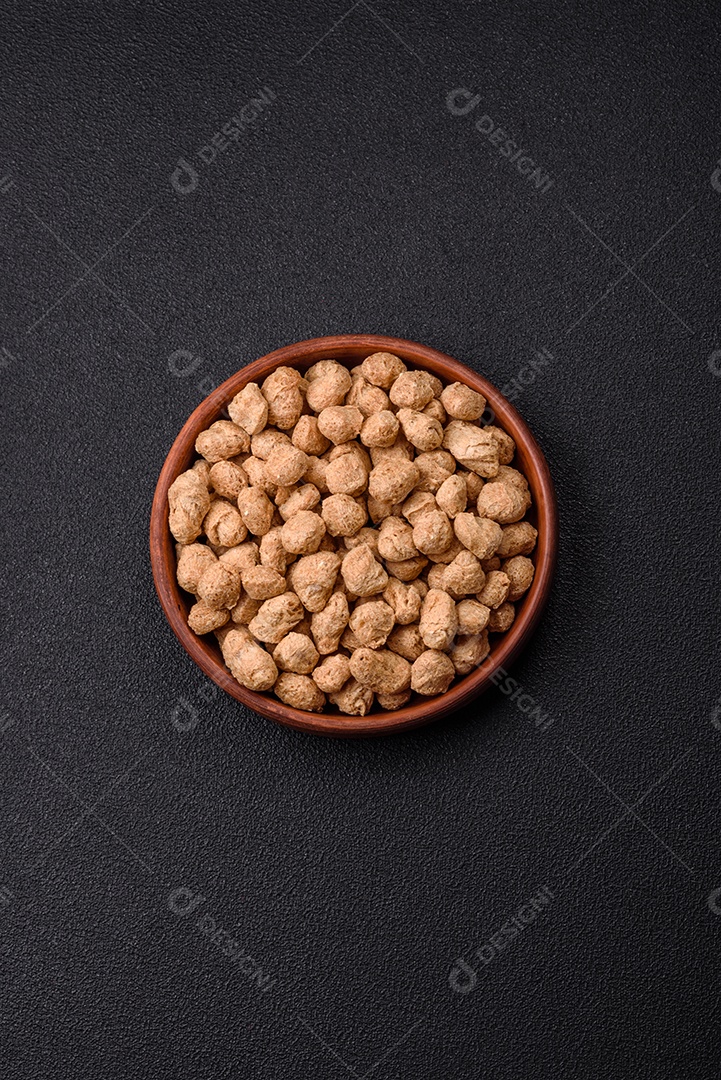 Pellets de carne de soja seca, alimentos dietéticos para cozinha vegana e vegetariana em fundo escuro de concreto