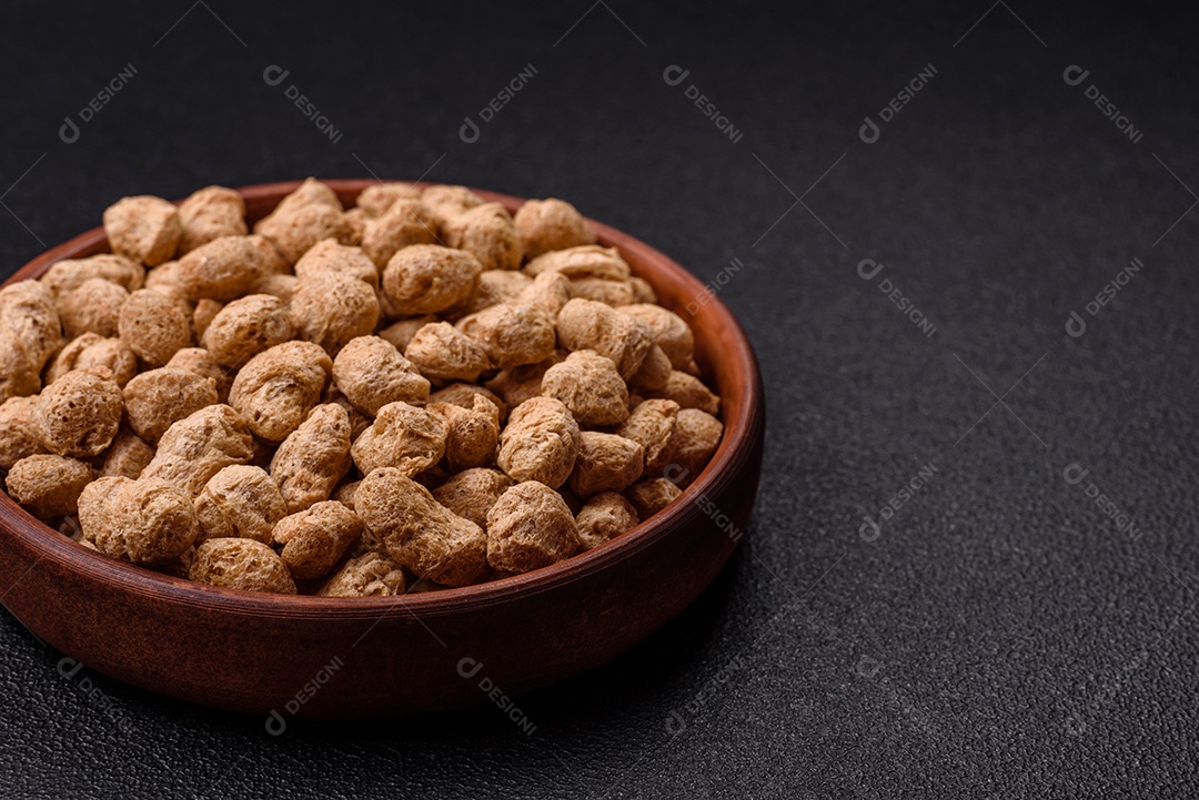 Pellets de carne de soja seca, alimentos dietéticos para cozinha vegana e vegetariana em fundo escuro de concreto