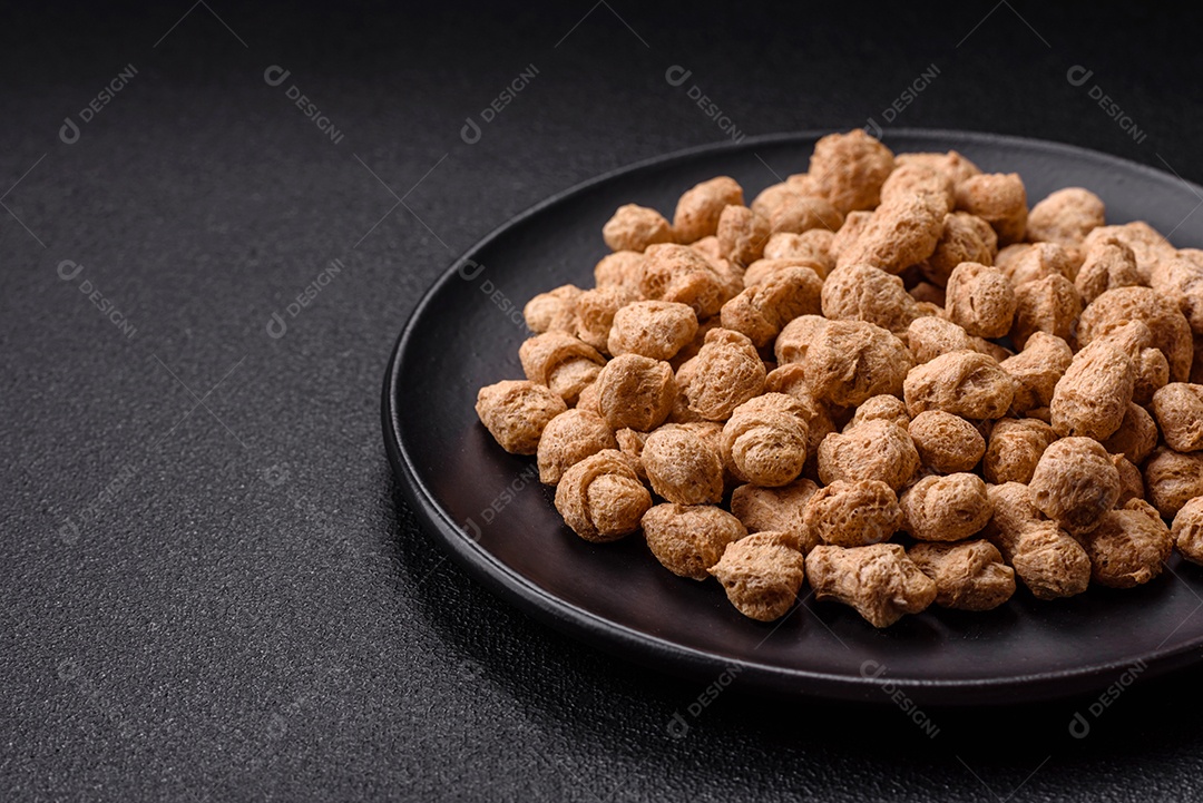 Pellets de carne de soja seca, alimentos dietéticos para cozinha vegana e vegetariana em fundo escuro de concreto