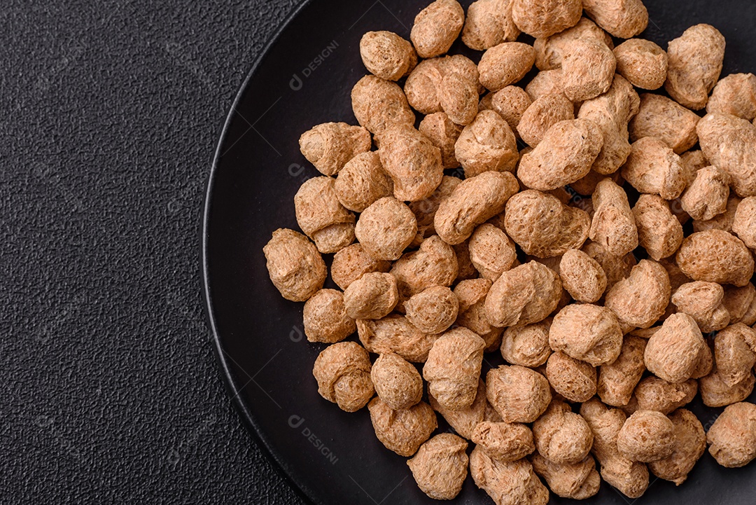 Pellets de carne de soja seca, alimentos dietéticos para cozinha vegana e vegetariana em fundo escuro de concreto