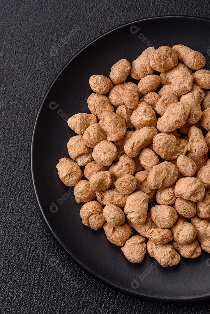 Pellets de carne de soja seca, alimentos dietéticos para cozinha vegana e vegetariana em fundo escuro de concreto