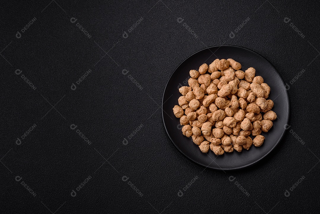 Pellets de carne de soja seca, alimentos dietéticos para cozinha vegana e vegetariana em fundo escuro de concreto