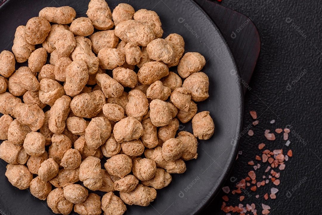 Pellets de carne de soja seca, alimentos dietéticos para cozinha vegana e vegetariana em fundo escuro de concreto