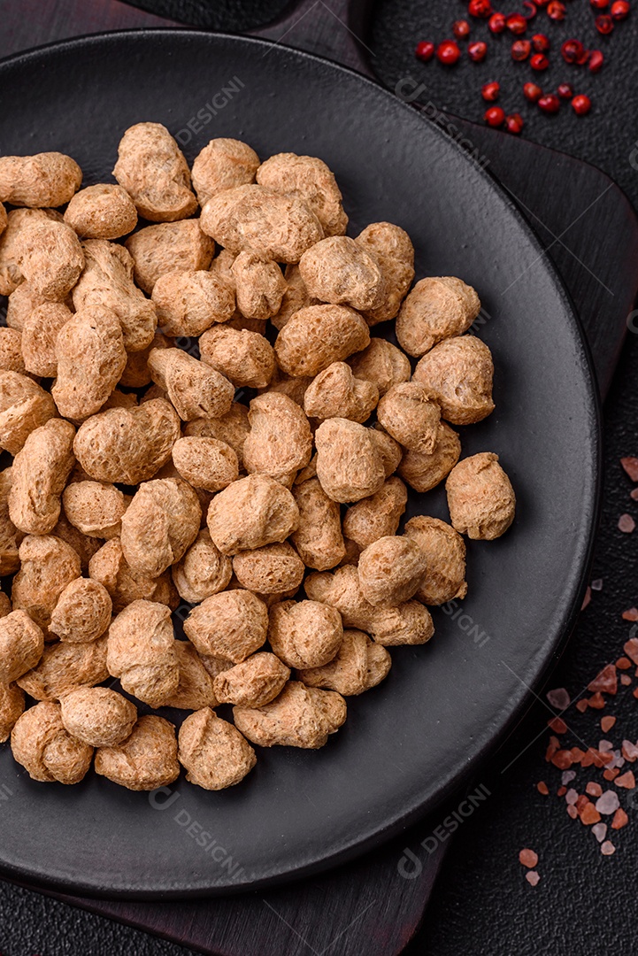 Pellets de carne de soja seca, alimentos dietéticos para cozinha vegana e vegetariana em fundo escuro de concreto