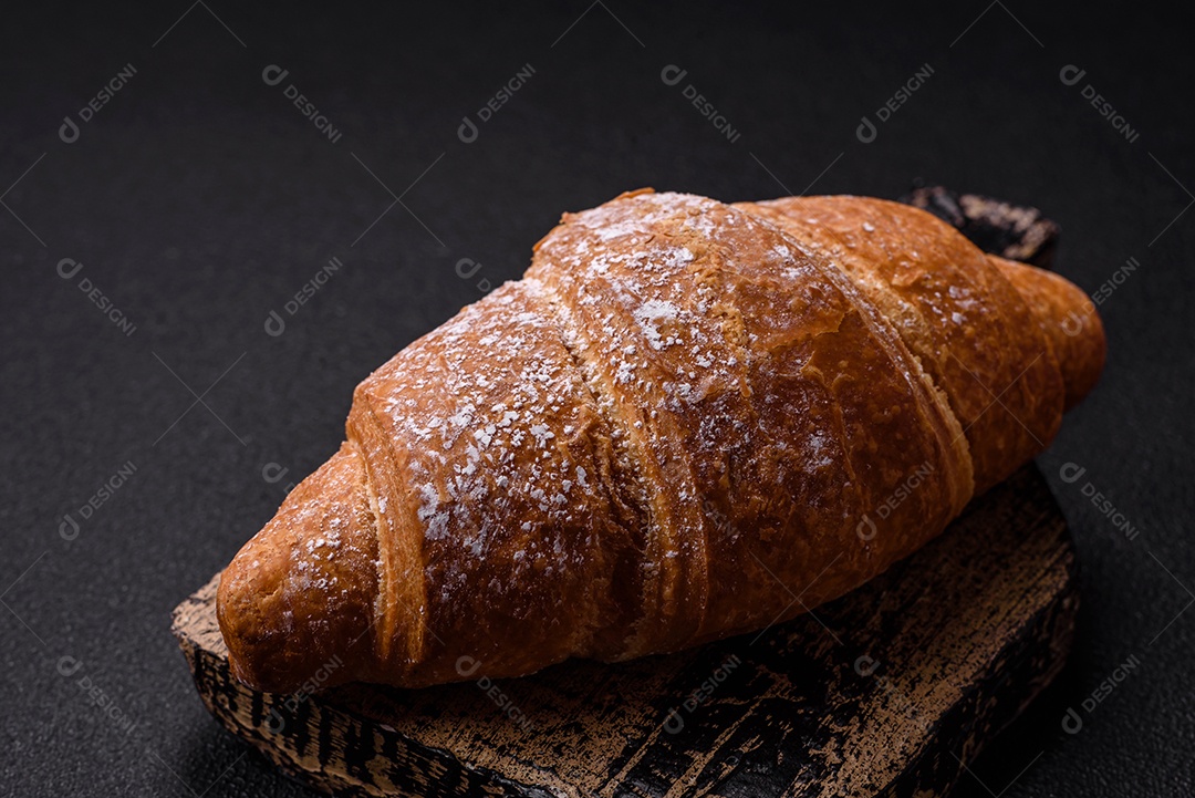 Delicioso croissant dourado crocante com recheio de chocolate sobre um fundo escuro de concreto