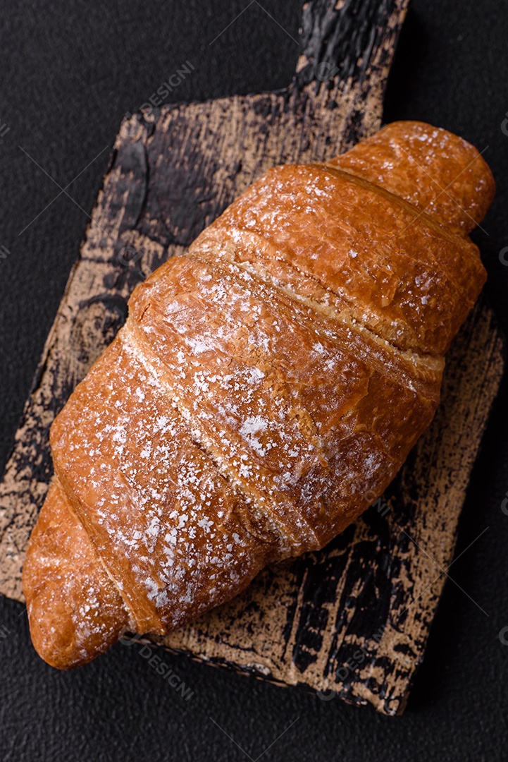 Delicioso croissant dourado crocante com recheio de chocolate sobre um fundo escuro de concreto