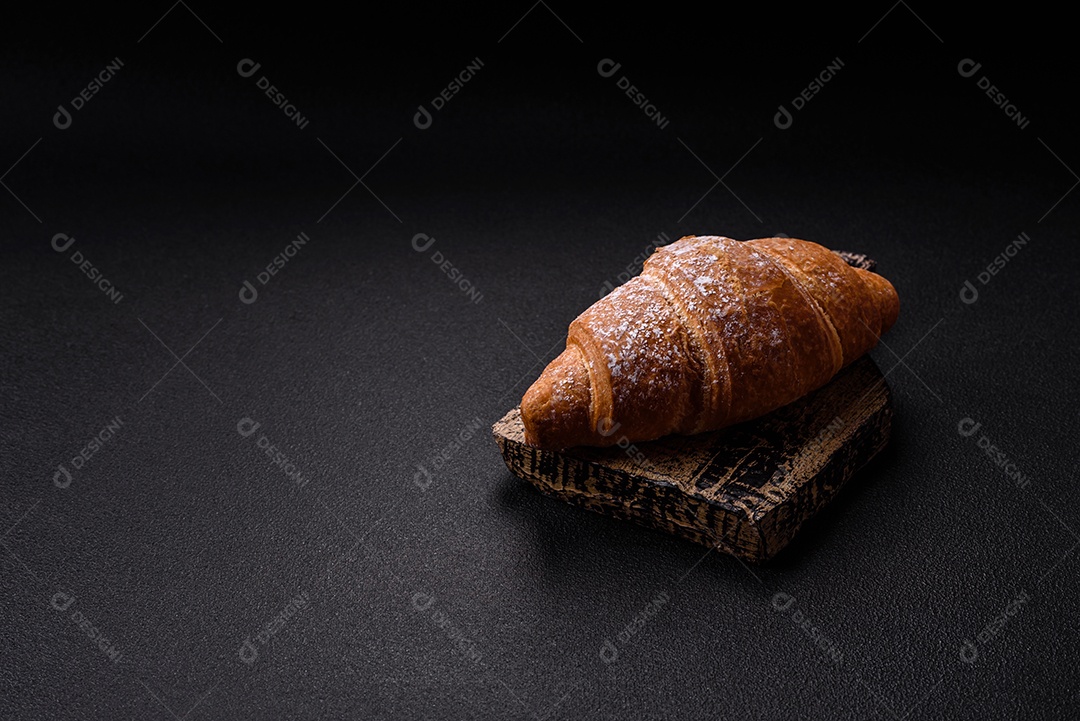 Delicioso croissant dourado crocante com recheio de chocolate sobre um fundo escuro de concreto