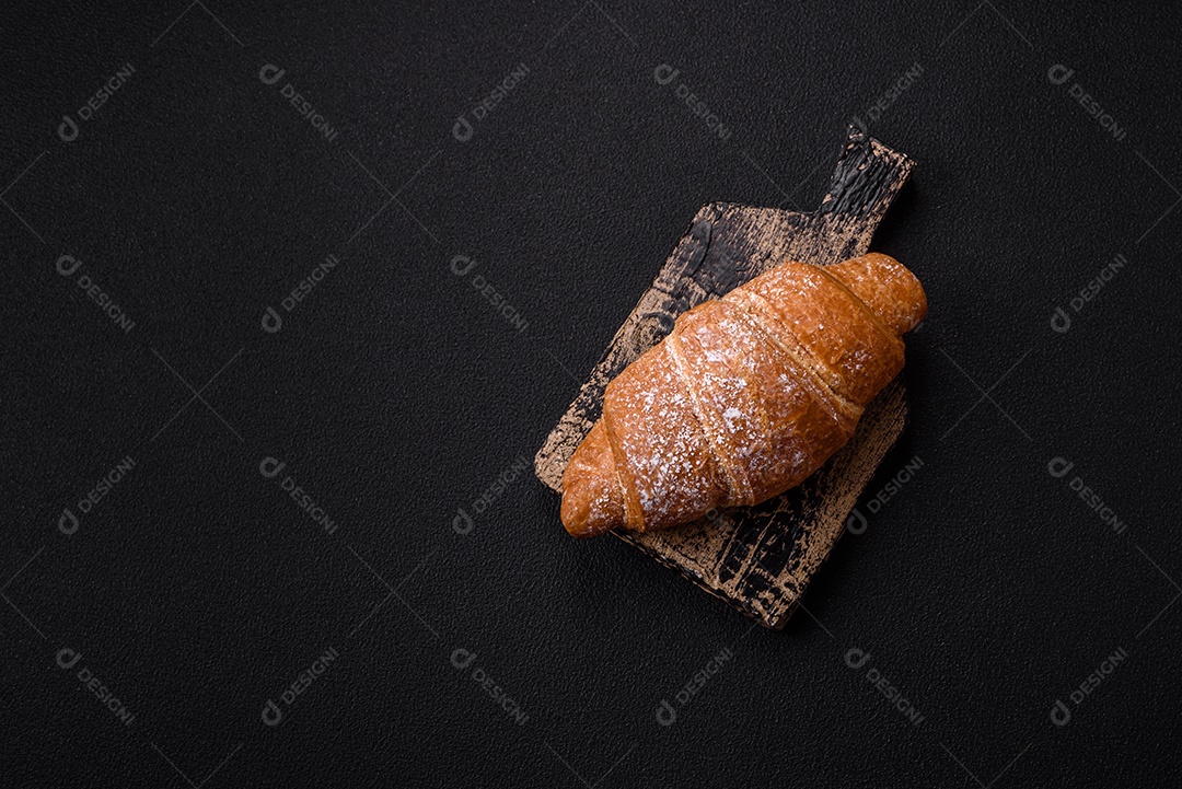 Delicioso croissant dourado crocante com recheio de chocolate sobre um fundo escuro de concreto