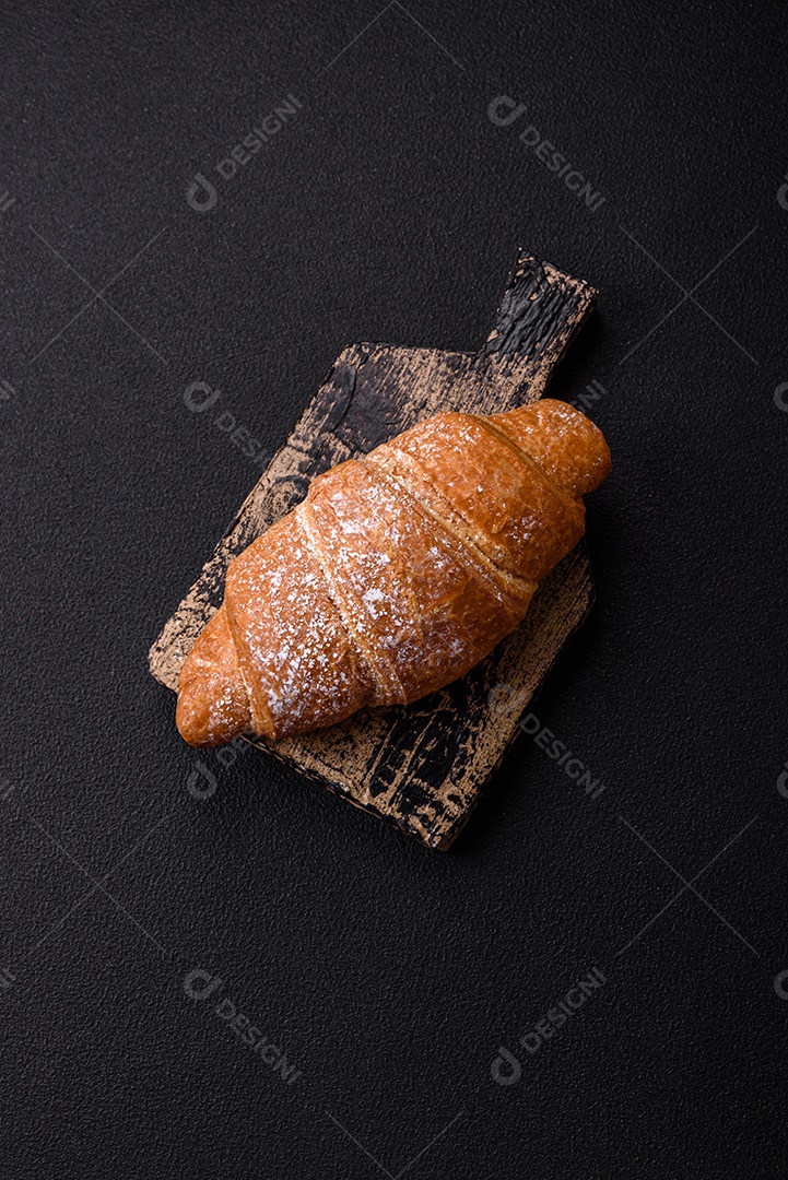 Delicioso croissant dourado crocante com recheio de chocolate sobre um fundo escuro de concreto