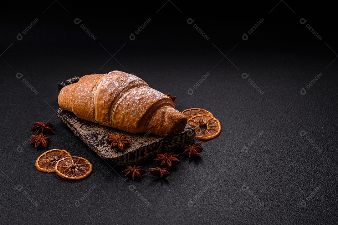 Delicioso croissant dourado crocante com recheio de chocolate sobre um fundo escuro de concreto